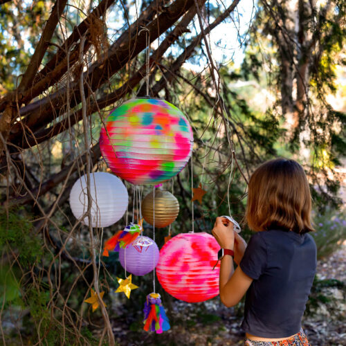 Girl hanging up lanterns in the trees