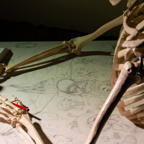 Skeleton leaning over sketched drawings