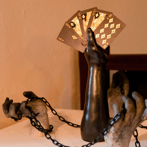 Sculpture of chained hands playing cards